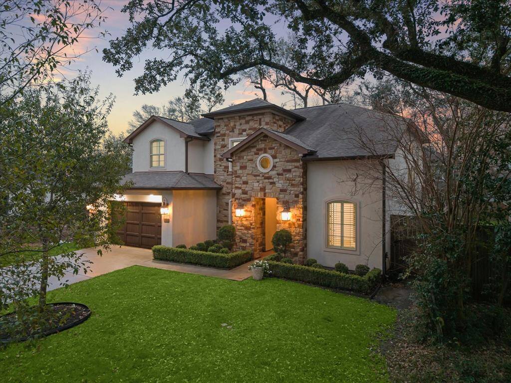 This charming two-story home features a stone and stucco facade, a welcoming front entrance with warm lighting, and a well-maintained lawn. The attached garage and inviting atmosphere make it an ideal choice for buyers seeking comfort and style.