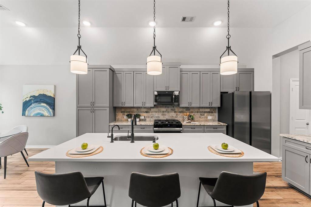 This kitchen highlights its beautifully updated quartz island, complemented by updated appliances and modern pendant lights.