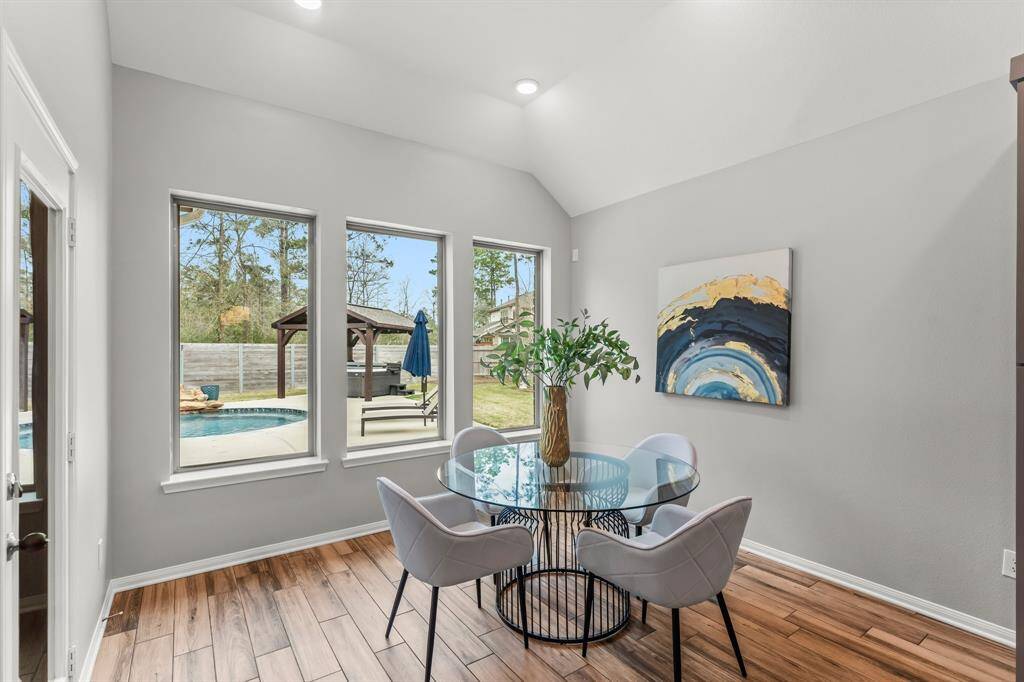 Bright dining area with large windows overlooking a backyard pool.