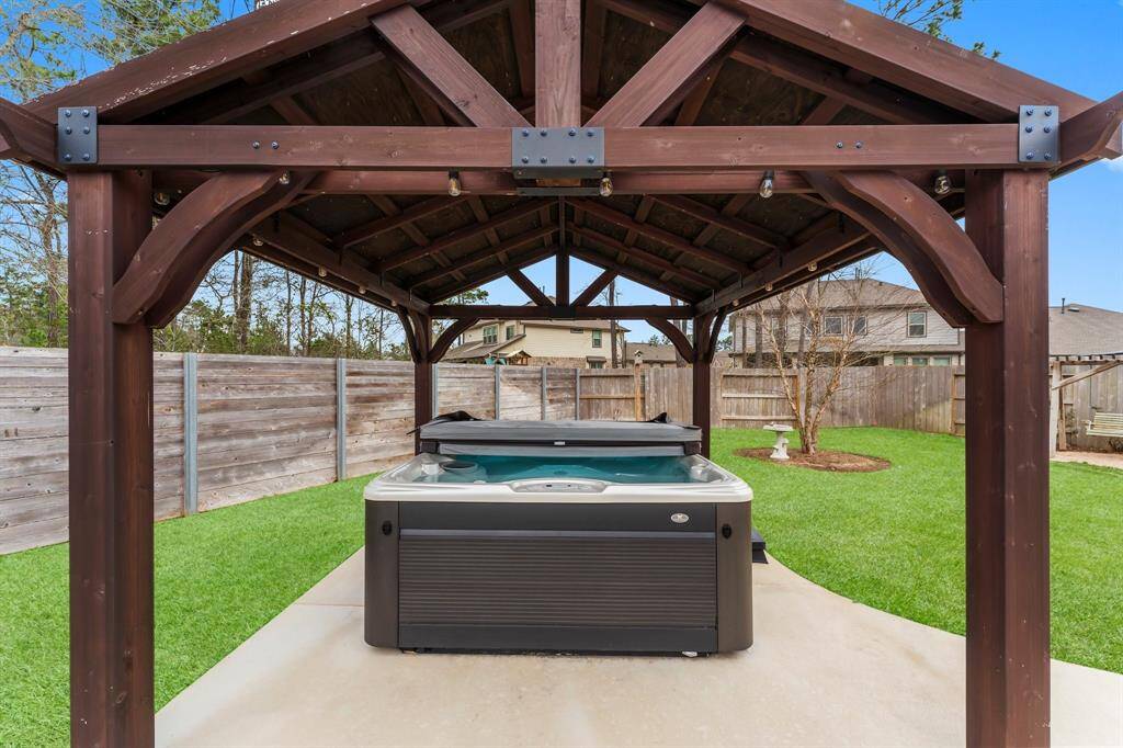 Relax in your hot tub under a charming pergola, glowing with string lights for year-round ambiance.  The attached cover keeps it sparkling clean, ready for quiet evenings or lively gatherings.  From summer fun to winter warmth, this inviting space welcomes you in every season.