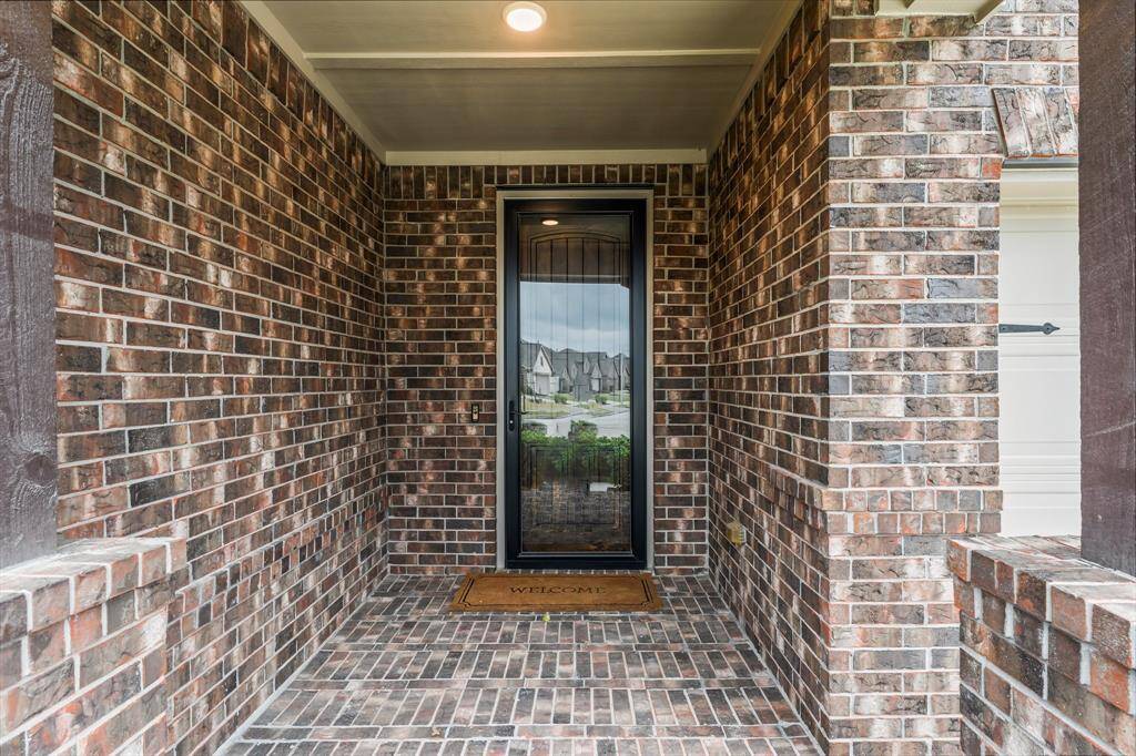 A welcoming front entrance with a brick exterior, featuring a covered porch area and a glass-paneled door, giving it a classic and inviting look.