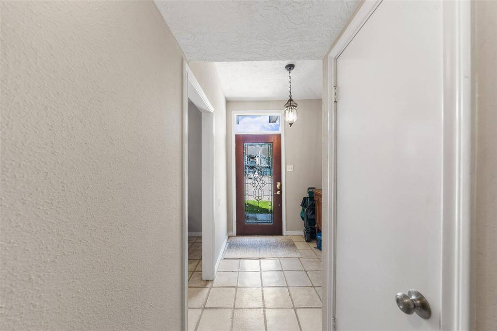 Entryway with a decorative glass front door, tiled flooring.