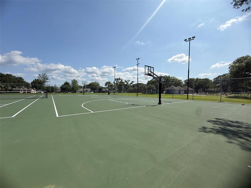 Sports area with well-maintained basketball and tennis courts, surrounded by greenery and set under a clear blue sky, ideal for recreational activities.