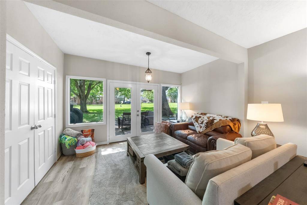 Bright living room with large windows and glass doors offering a view of a lush, green yard. Through the windows offers a view of the waters of Lake Conroe.