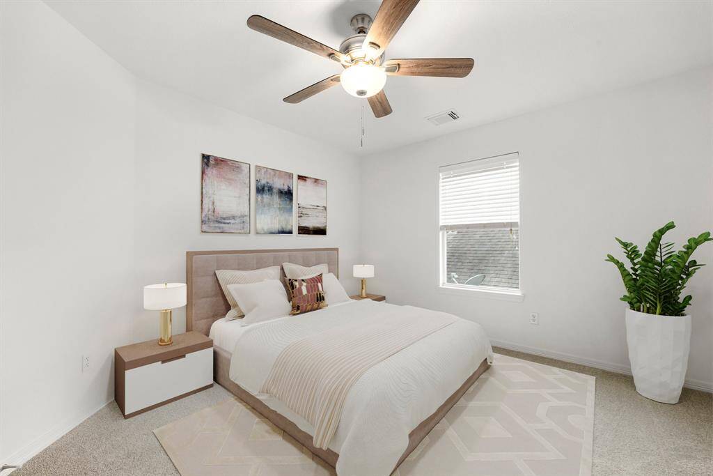 Secondary bedroom features plush carpet, fresh neutral paint, dark stained ceiling fan with lighting and a large window with privacy blinds.