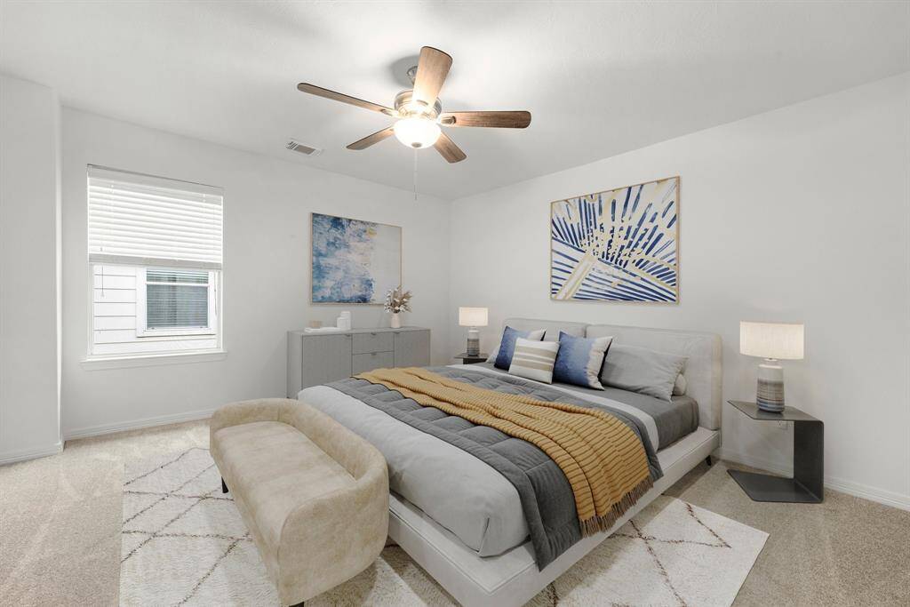 Secondary bedroom features plush carpet, fresh neutral paint, dark stained ceiling fan with lighting and a large window with privacy blinds.