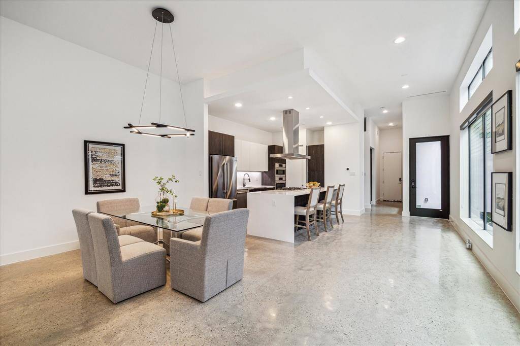 This open-concept layout flows effortlessly from the chef’s kitchen into the dining and living space, the kitchen featuring quartz counters, dramatic custom cabinetry, and designer lighting that elevates every inch.