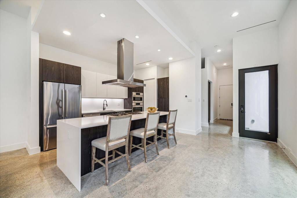 Step into polished perfection—concrete floors, soaring ceilings, and a sexy, two-tone kitchen with a statement island that’s made for both cocktails and conversation.