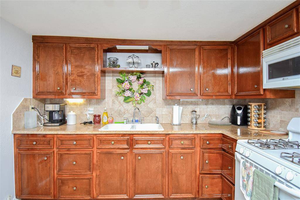 The kitchen features a sleek tile backsplash for easy cleaning, abundant cabinet storage, and a gas range stove- combining style and functionality for the home chef.