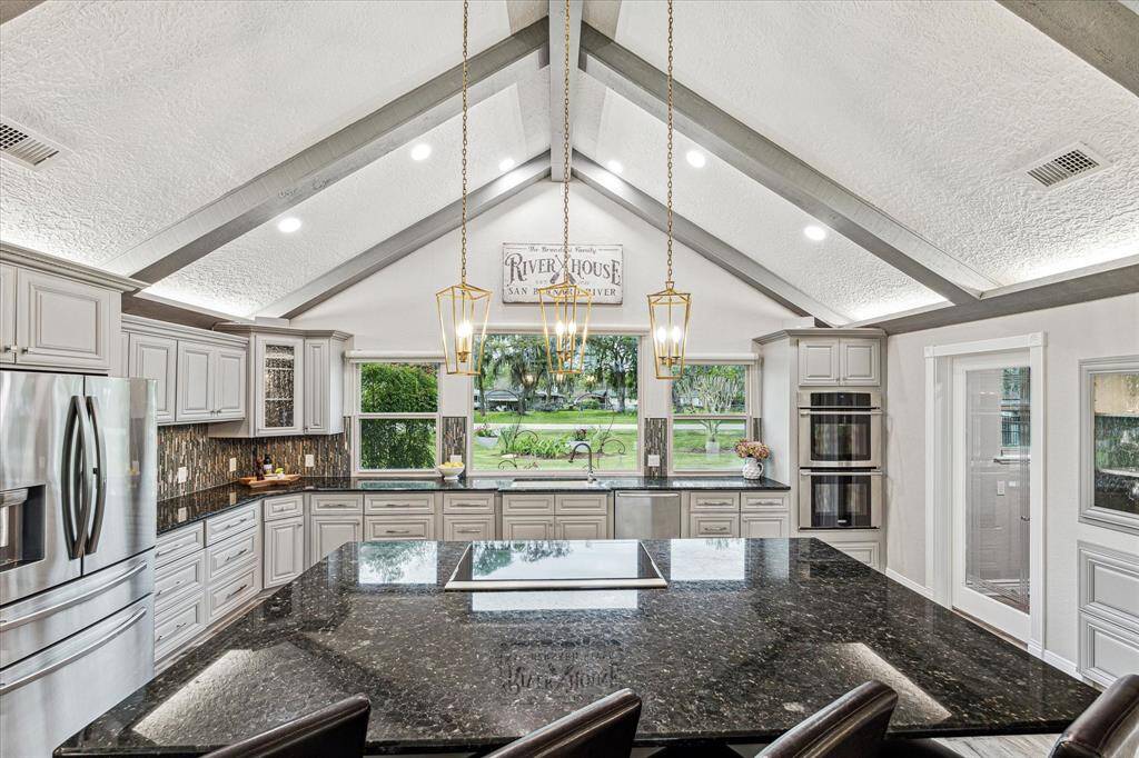 Fabulous features in this island kitchen include granite countertops, designer tile backsplash, freshly painted cabinetry, upgraded lighting, a massive walk-in pantry, and Wolf brand induction cooktop.   Note that the double ovens were replaced after photos were taken with new units.