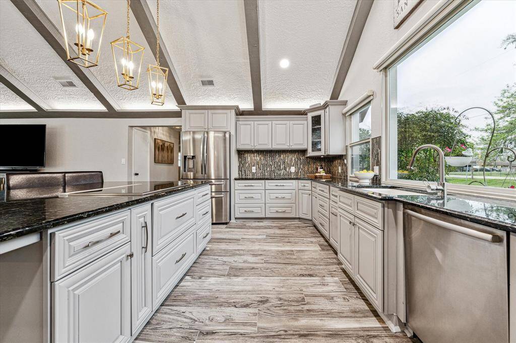 Ditch the takeout and cook from home more often. This fully loaded kitchen offers freshly painted cabinetry, sleek stainless steel appliances, granite countertops, designer tile backsplash and lighting, an upgraded sink, Wolf brand induction cooktop, and spectacular views through the oversized windows.