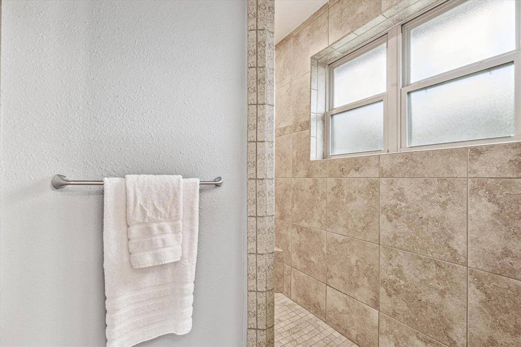 The walk-in shower in the primary suite is fully tiled and offers large opaque windows allowing the space to fill with natural light.