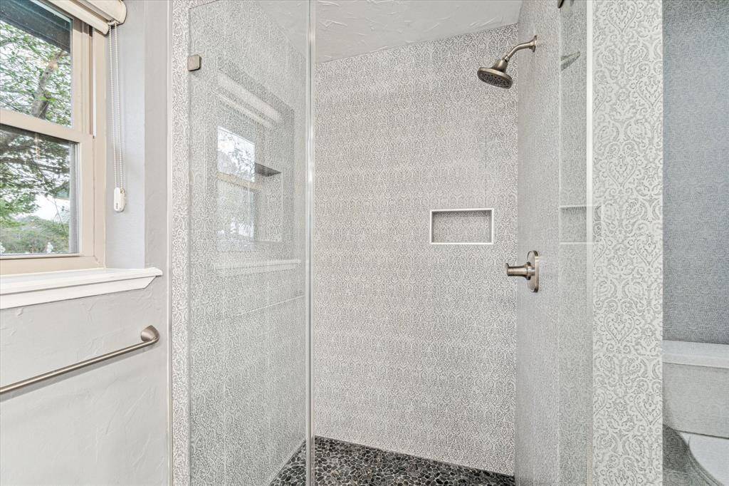 The ensuite features a beautiful walk-in shower with designer tile, upgraded fixtures, shampoo ledges, and frameless glass.