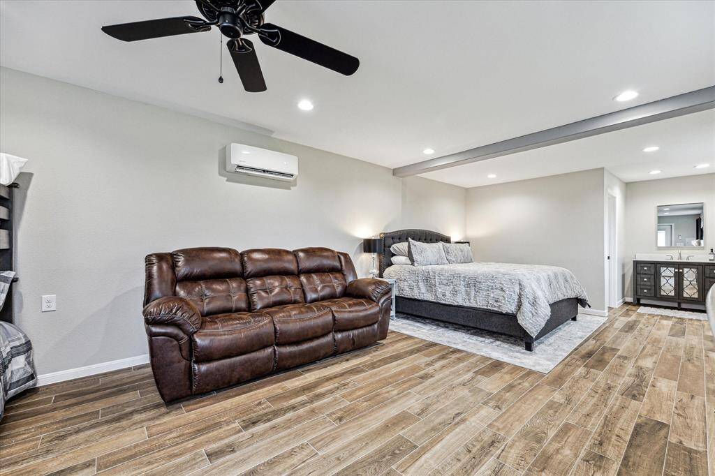 Guest quarters feature wood-look tile flooring, fresh neutral paint, a wood beam and recessed lights in the ceiling, an ensuite full bathroom, and plenty of space for furnishings.
