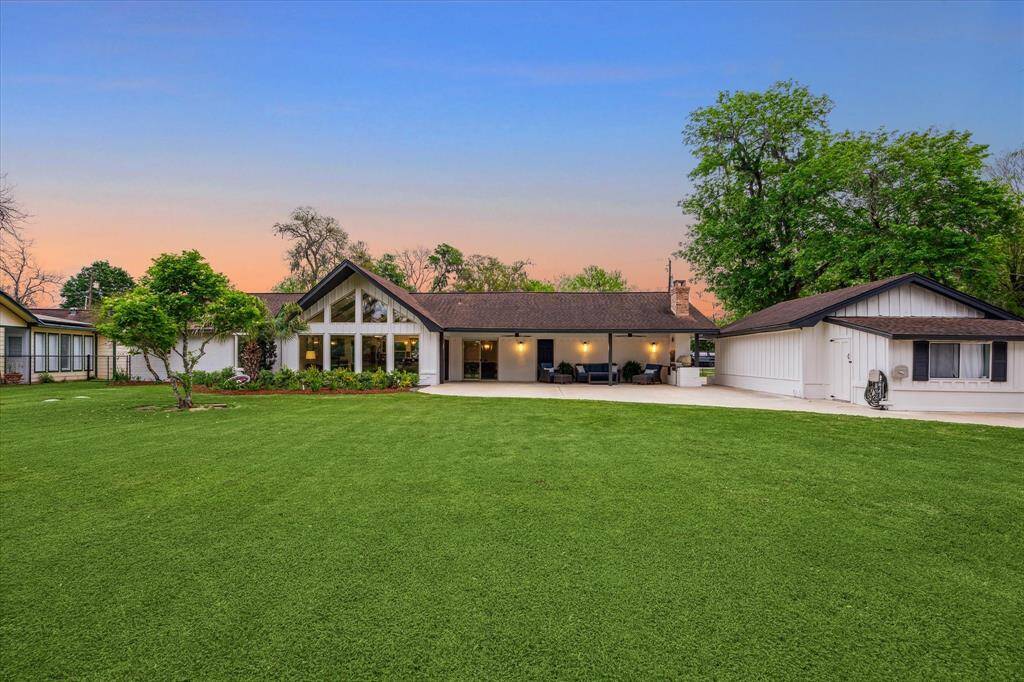 Stunning by day or night. This view of the back of home from the water shows a sprawling grassy lawn, massive patio, covered patio and guest quarters.