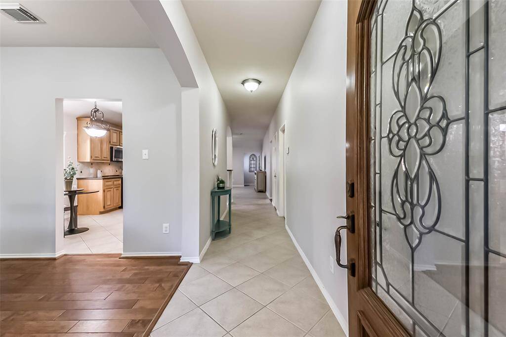 Welcoming entrance with a beautiful decorative glass front door that makes a stylish first impression. Long hallway draws you in and leads gracefully to the dining room, kitchen, and living area.