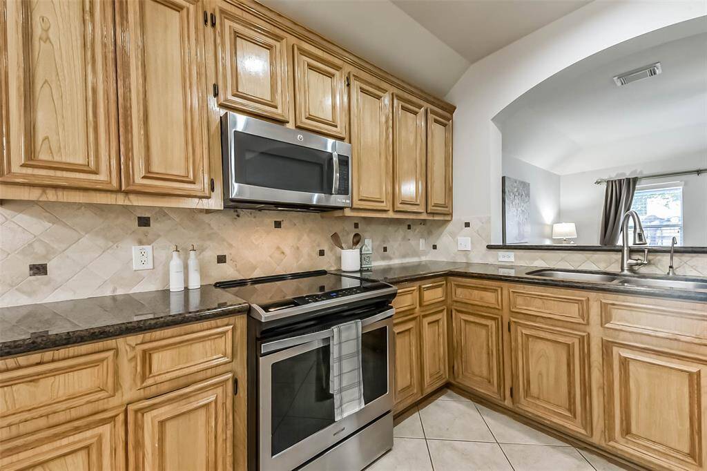 ravertine tile backsplash with granite accents adds a designer touch.