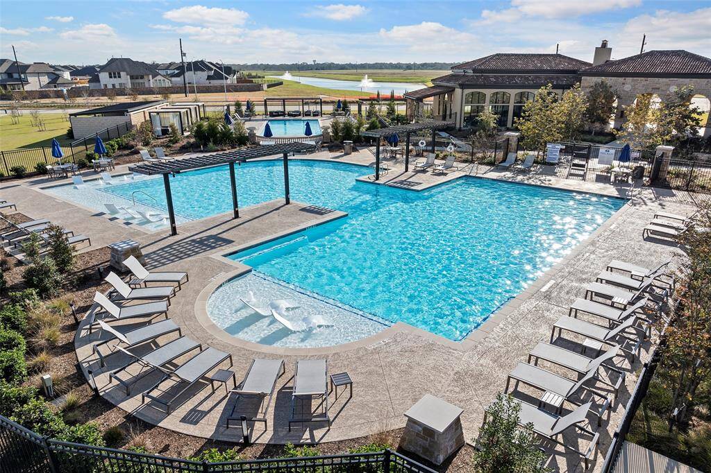 Community pool area includes in-water loungers, shaded pergolas, and plenty of seating—designed for both relaxation and gathering with a backdrop of lake views and fountains.