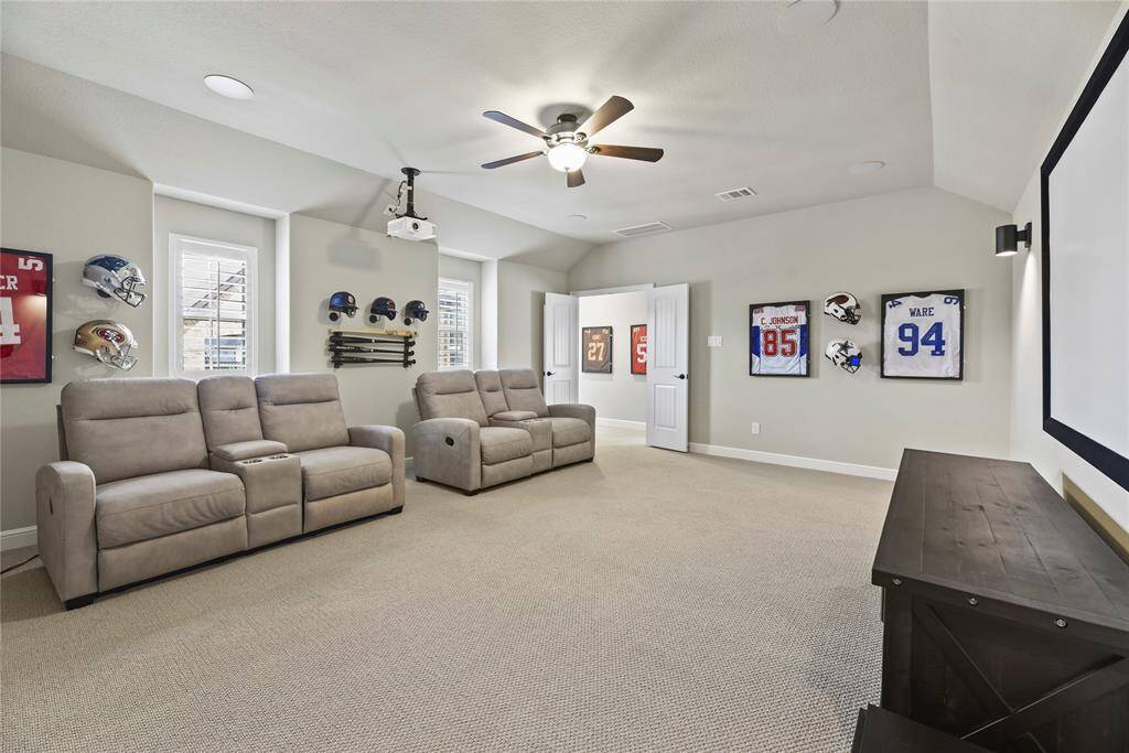 Spacious home theater room with comfortable recliner seating, sports memorabilia, and a large screen for a great viewing experience.