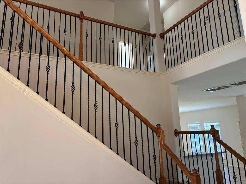 This photo features a staircase with elegant wooden handrails and black metal balusters, creating a stylish and open feel. The upper landing is also visible, enhancing the spaciousness of the home.