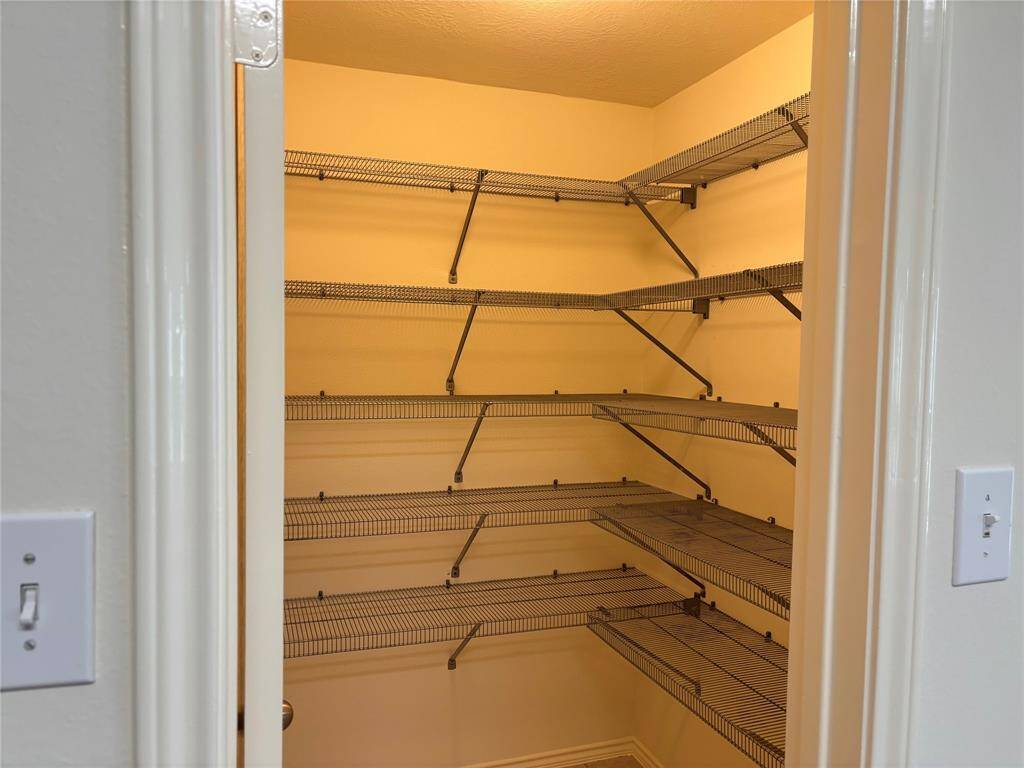 This photo shows a spacious pantry with multiple wire shelves, perfect for organized storage. The lighting and neutral walls create a bright, welcoming space.