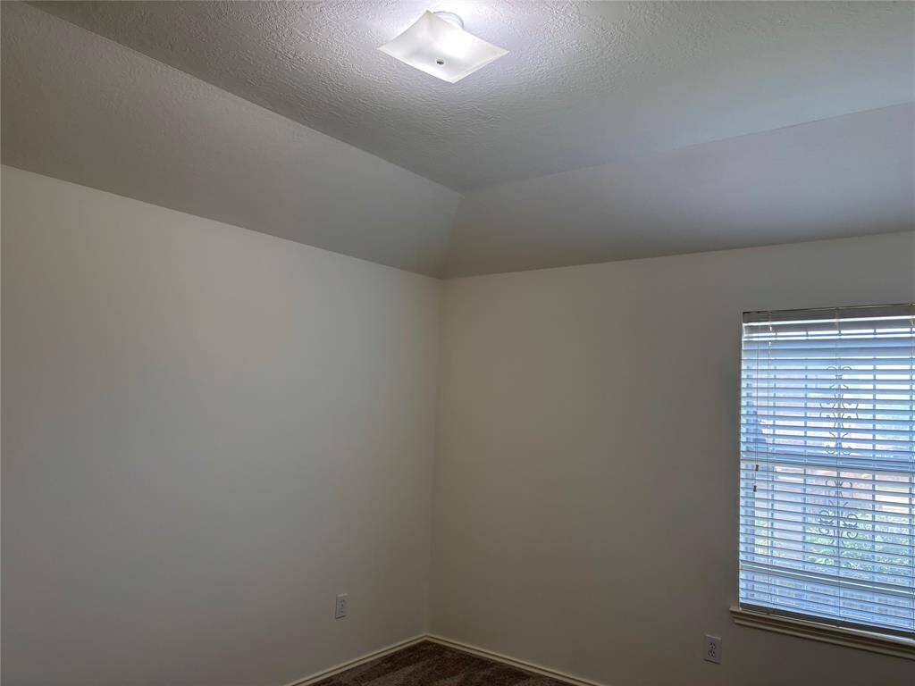 This room features neutral walls, a ceiling fan with lights, carpeted flooring, and a window with blinds, providing a comfortable and versatile space.