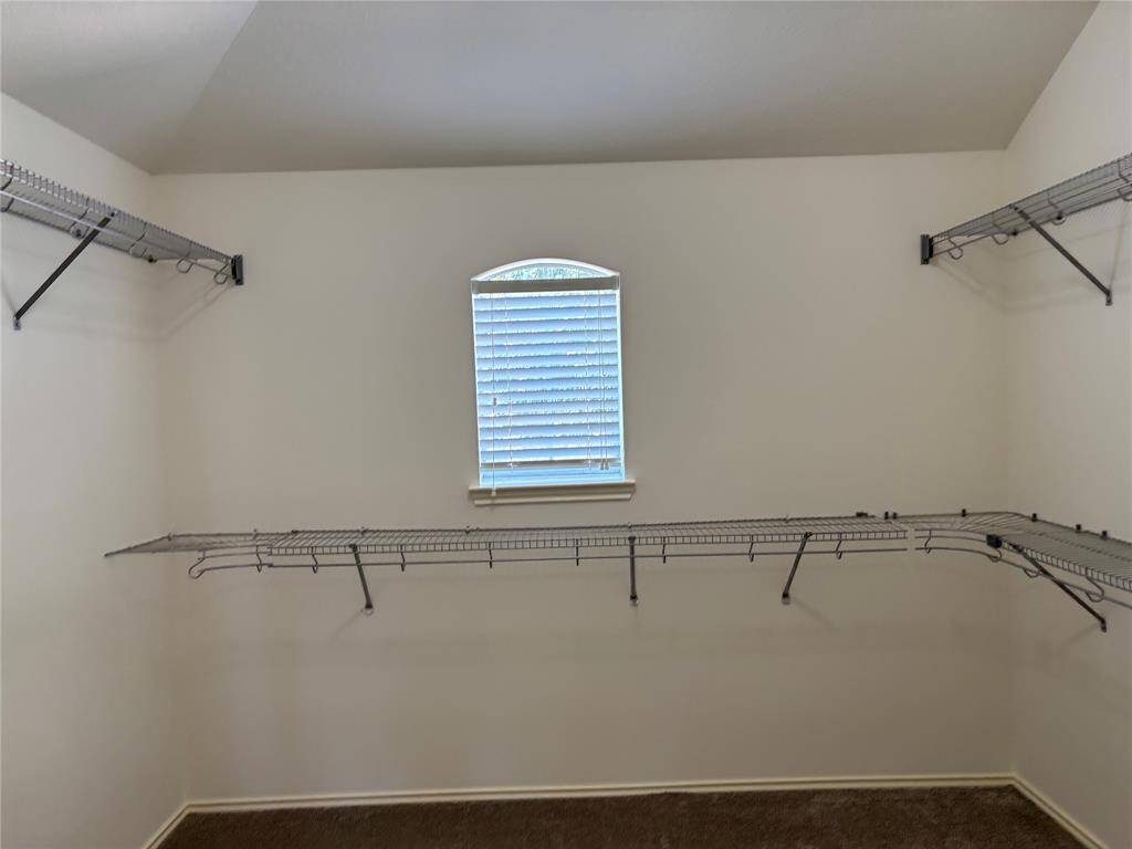Spacious walk-in closet with wire shelving on three walls and a small window with blinds, providing natural light.