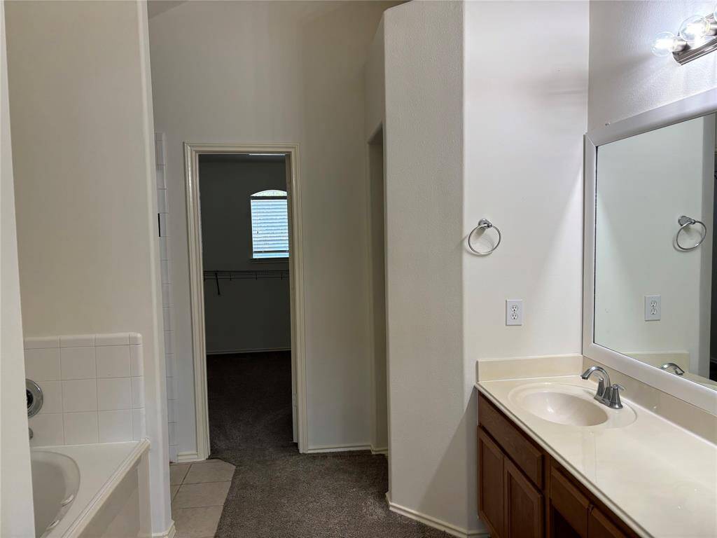 Primary Bathroom with dual vanity and long mirror and a shower and jetted tub combo