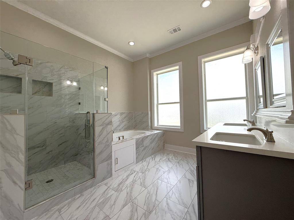 Natural light flows into the primary bath from twin windows. Enjoy the glass framed shower & soaking tub.