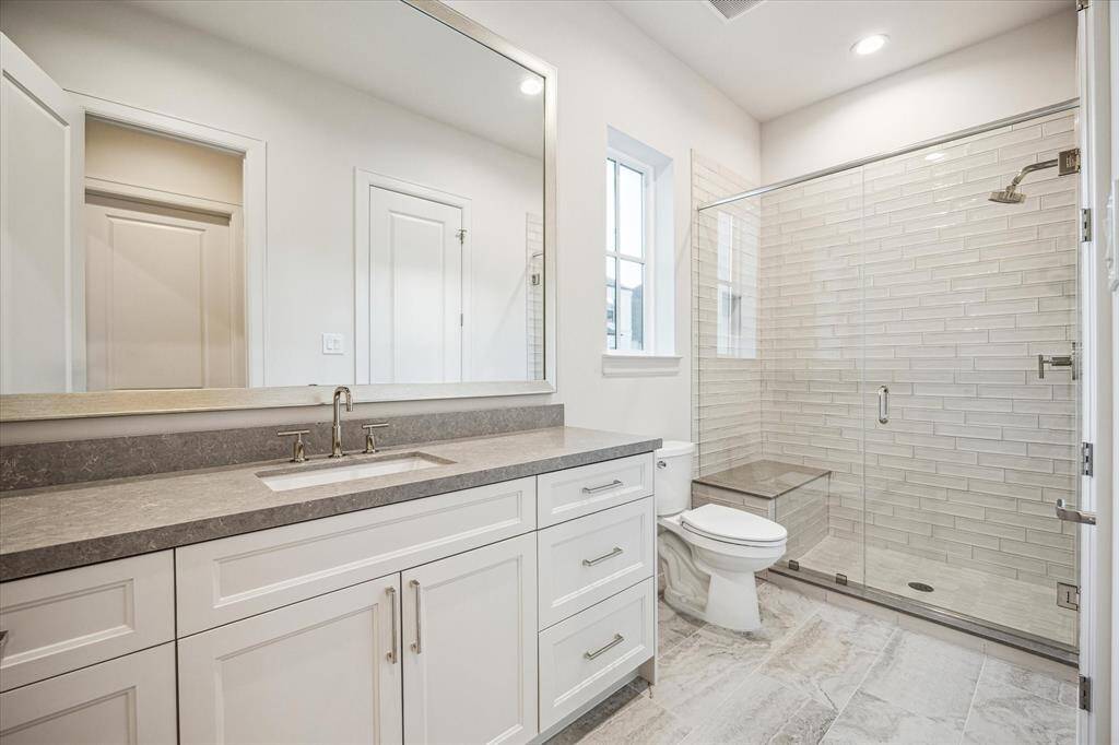 Guest bath with spacious walk-in shower and polished quartz countertop.