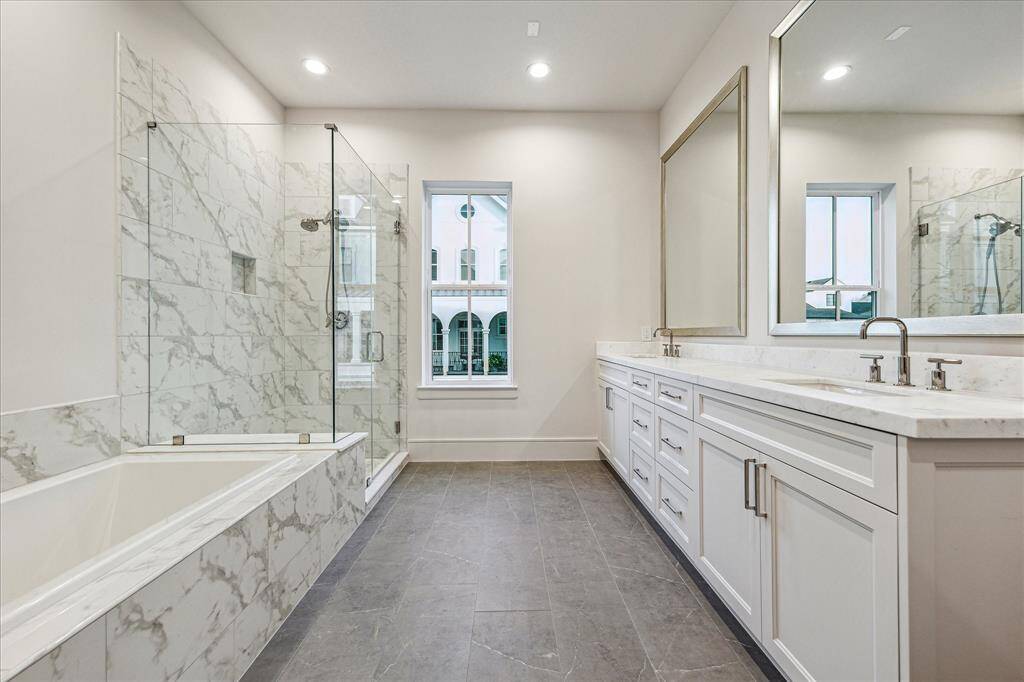Primary ensuite bathroom with honed marble countertops, double sinks, large tub and spacious walk-in shower.