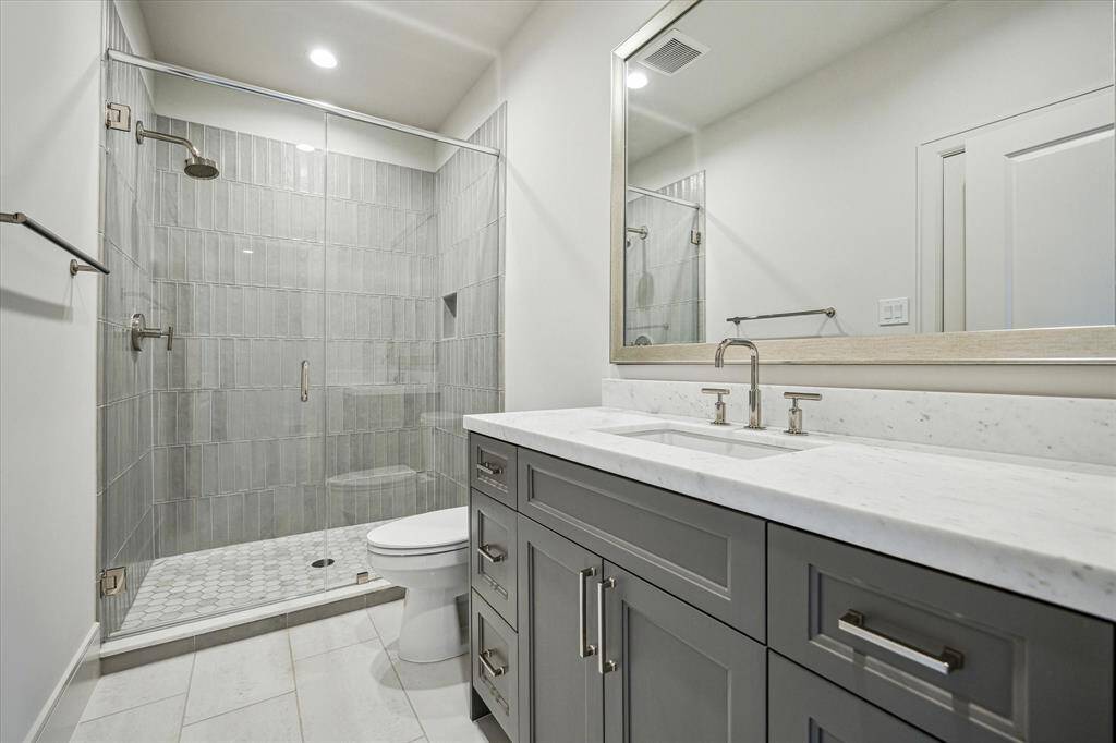 Guest bath walk-in shower with mosaic flooring and honed marble countertops.