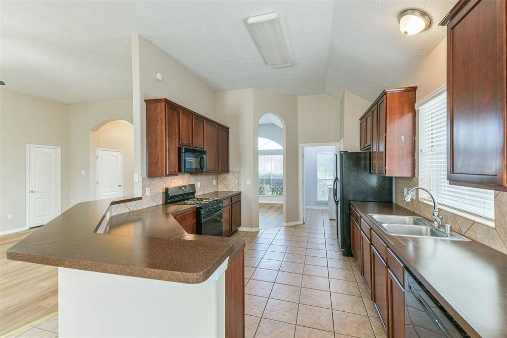 Functional kitchen with gas stove, oven, and included refrigerator.