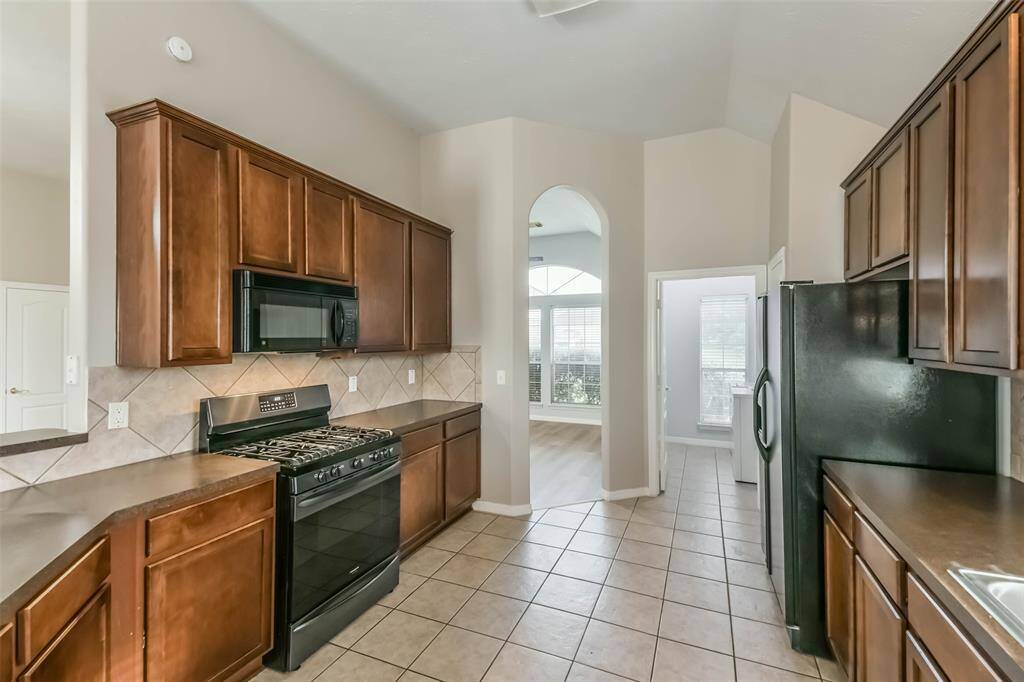 Functional kitchen with gas stove, oven, and included refrigerator.