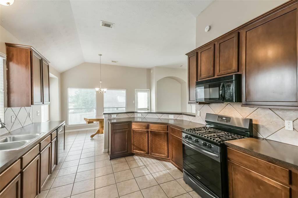 Functional kitchen with gas stove, oven, and included refrigerator.