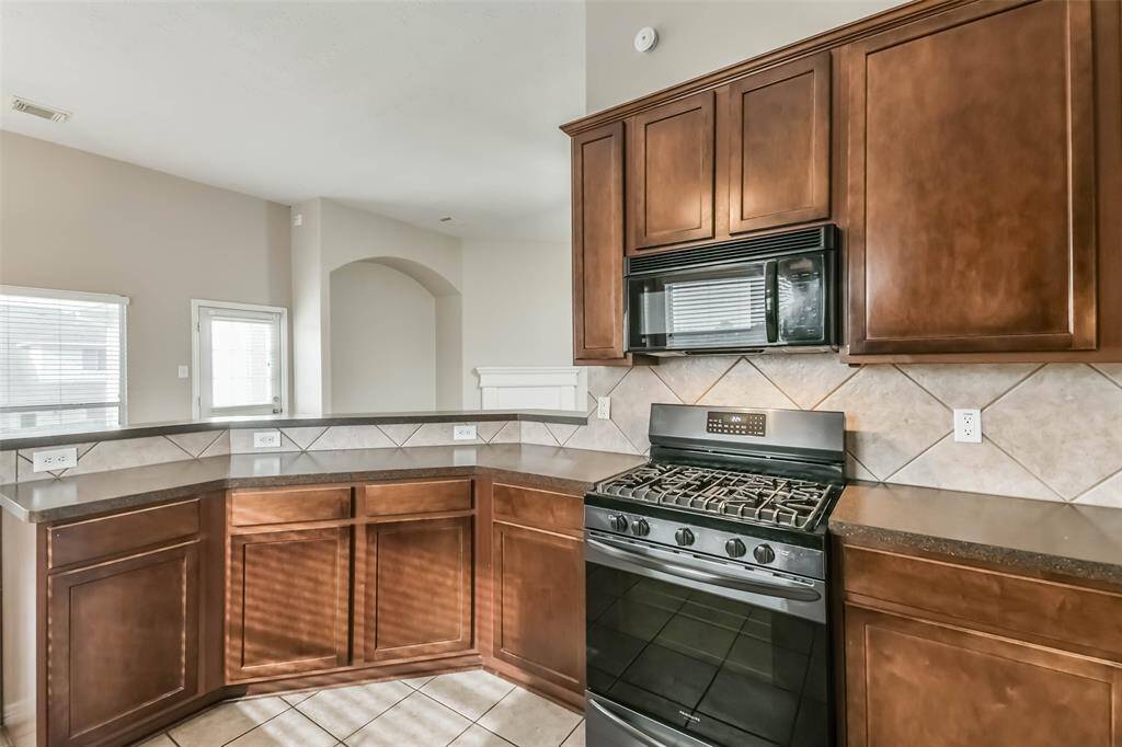 Functional kitchen with gas stove, oven, and included refrigerator.
