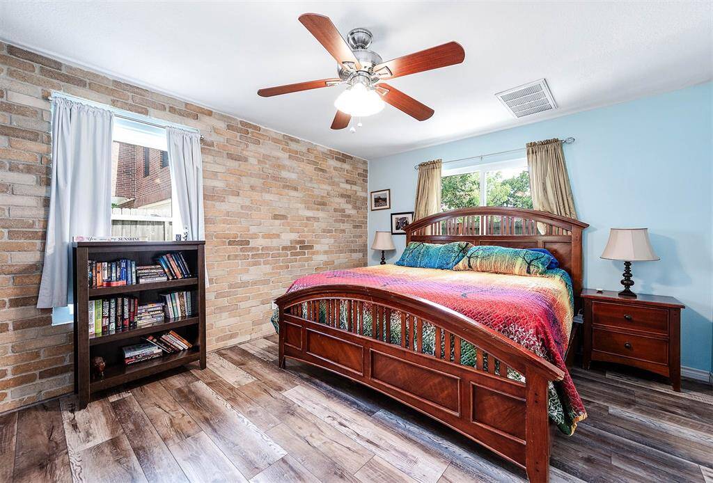 Primary bedroom features new flooring (2023), ceiling fan, and windows.