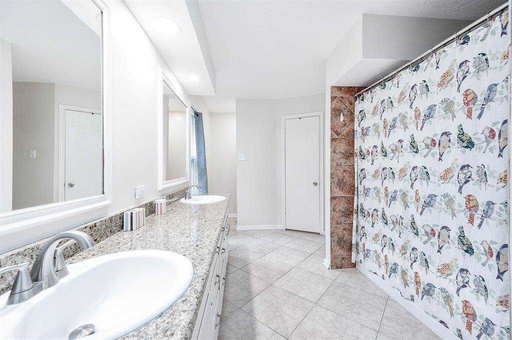 Ensuite bathroom features double sinks, granite counter tops, and tile flooring.