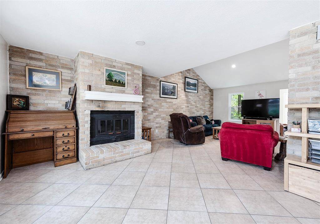 Living room showcases tile flooring, brick accents, recessed lighting, and natural lighting.