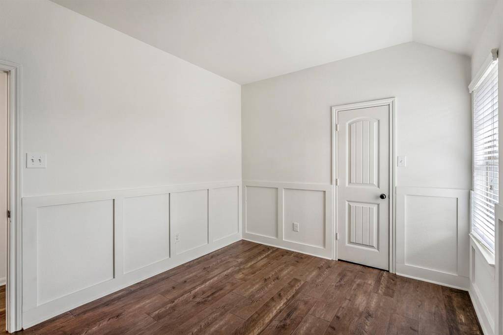 Bright and inviting upstairs room with elegant wainscoting and rich wood flooring.