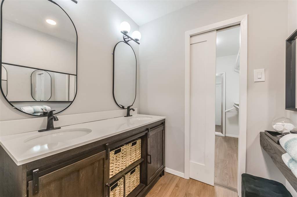 REMODELED primary bathroom featuring double sinks, and modern farmhouse mirrors. Makeup vanity is located opposite the sinks. Large walk-in closet!