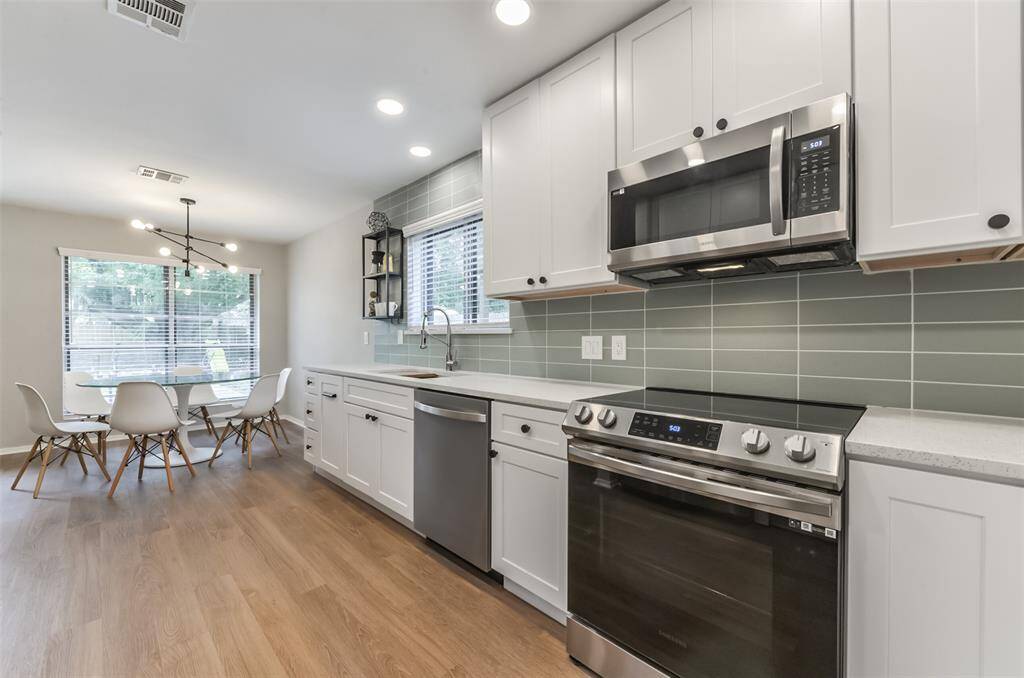 RECENT KITCHEN featuring BRAND NEW STAINLESS STEEL APPLIANCES, glass tile backsplash and modern QUARTZ COUNTERS.