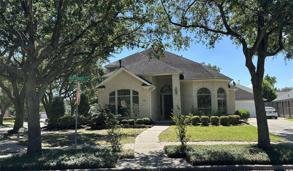 Charming Corner Lot Home with Elegant Curb Appeal Welcome to this beautifully maintained single-family home located on a desirable corner lot in a serene, tree-lined neighborhood. This light brick residence features a striking arched window design, high-pitched rooflines, and a spacious front entryway, creating a warm and welcoming impression. The manicured landscaping includes mature trees providing ample shade, trimmed hedges, and well-kept flower beds, enhancing the home's curb appeal.