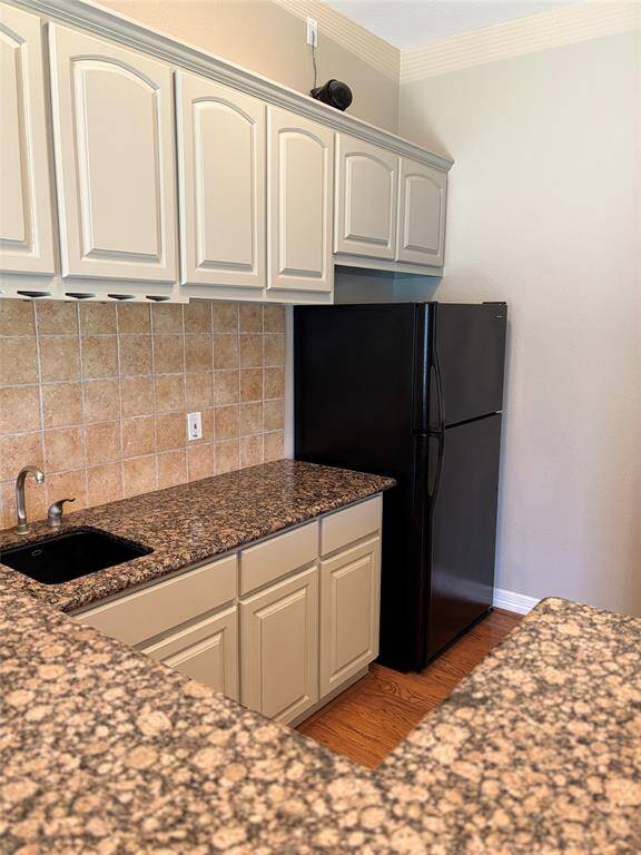 A bright, open kitchen with vaulted ceilings and hardwood floors. It features modern pendant lighting, a central island with a cooktop, and ample cabinetry. A cozy dining area and large windows offers natural light.