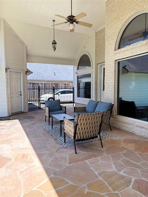 Spacious covered patio with high ceilings, elegant lighting, ceiling fans, and stone flooring—perfect for outdoor relaxing or entertaining year-round.