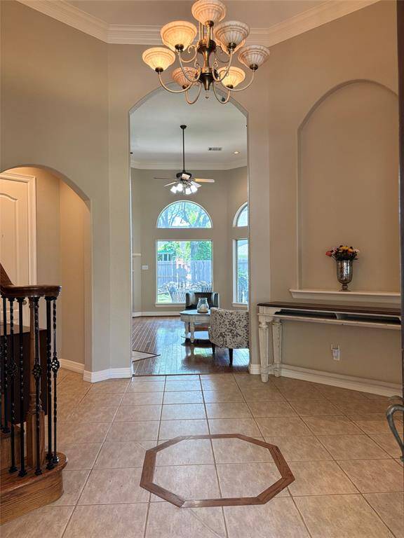 The living room offers a bright and inviting space with rich hardwood flooring, a cozy gas fireplace, and soaring ceilings framed by elegant trim work. Large arched windows and a glass door allow natural light to flood the room and provide a beautiful view of the backyard. Whether relaxing by the fire or entertaining guests, this space blends comfort and sophistication effortlessly.