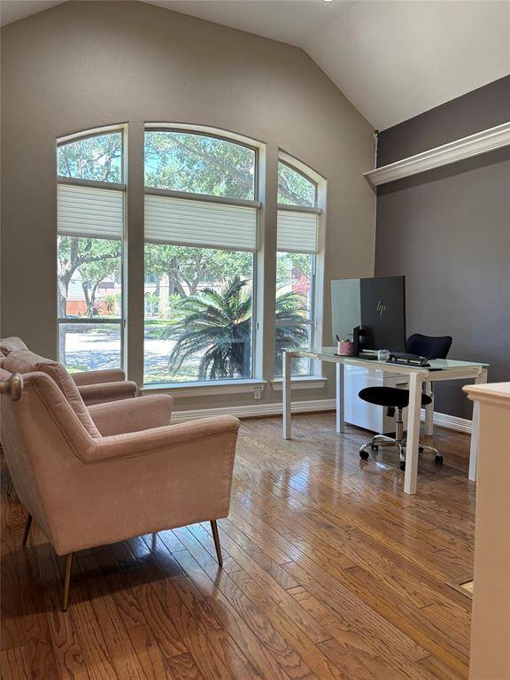 The living room features a striking gas fireplace framed with tile and elegant molding, creating a beautiful focal point. Hardwood floors, soaring ceilings, and arched windows complete this warm and inviting space with views of the backyard.