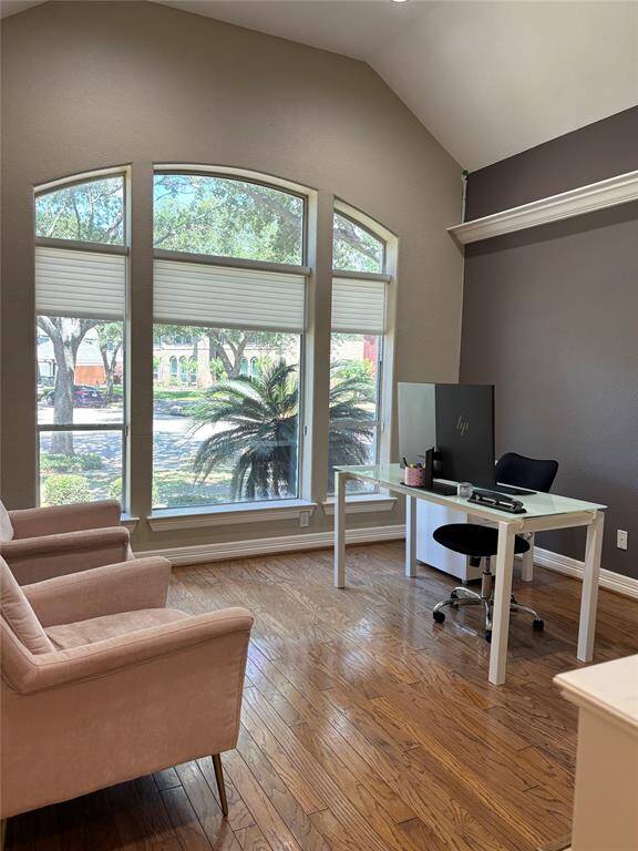 Elegant dining room with vaulted ceiling, rich hardwood floors, and large arched windows offering abundant natural light and scenic views. Features a classic chandelier and inviting architectural details.