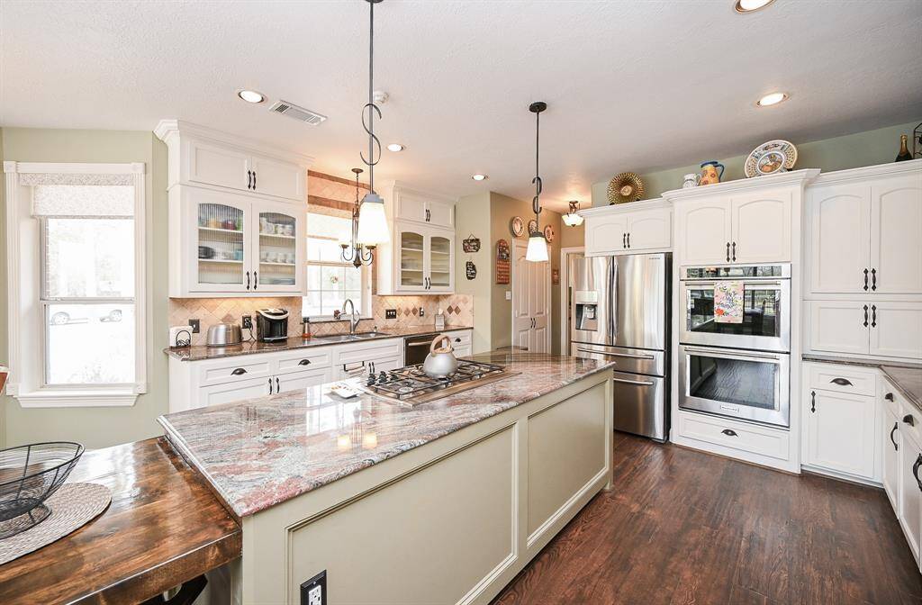 Open kitchen area with stainless steel appliances. Counter depth refrigerator. Kitchen aid double oven. Motorized cooktop vent, glass cabinet doors. Under cabinet lighting, new cabinet hardware and freshly painted lower cabinets. New faucets in kitchen and laundry rooms.