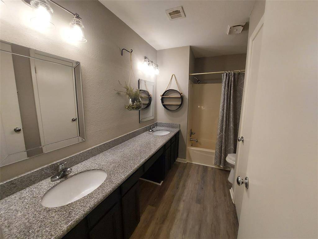One piece tub shower combo and double sinks with granite counter tops and recent vinyl floors.